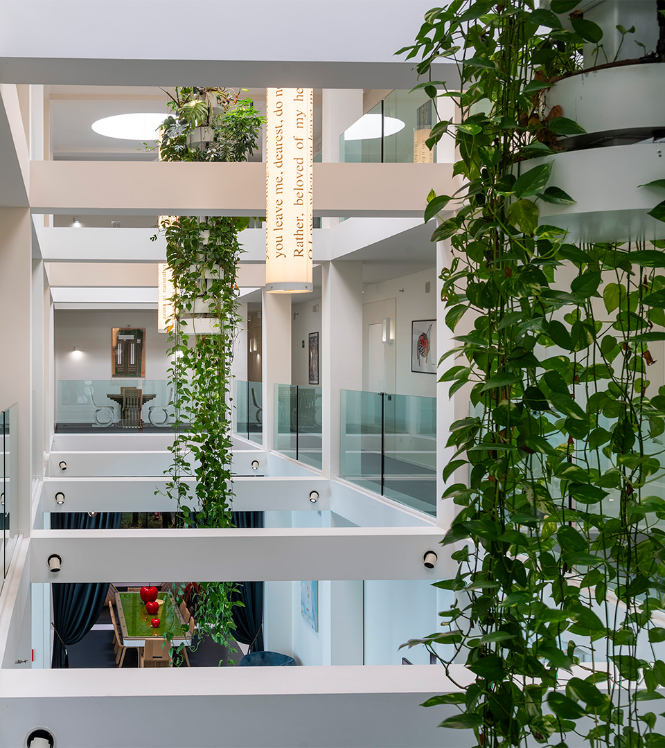 Corridoi luminosi con piante sospese e vista centrale sugli interni dei vari piani