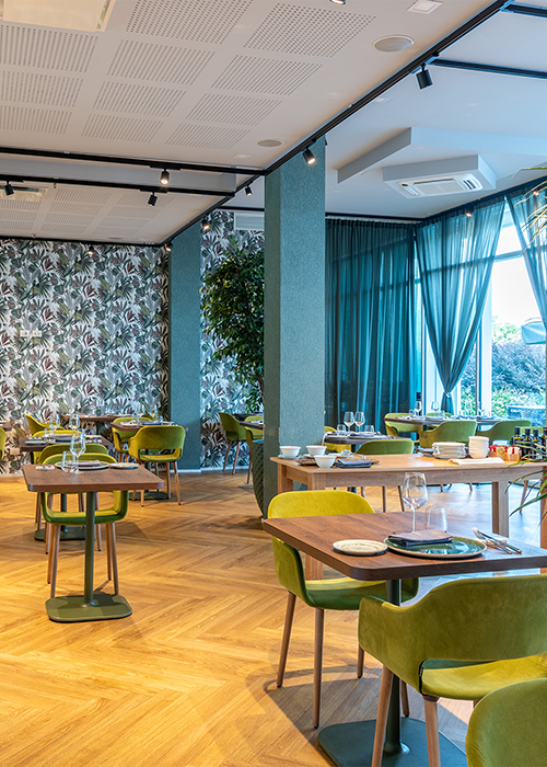 Tavoli del Lounge Bar esterno sotto ampi ombrelloni bianchi con vista sul verde