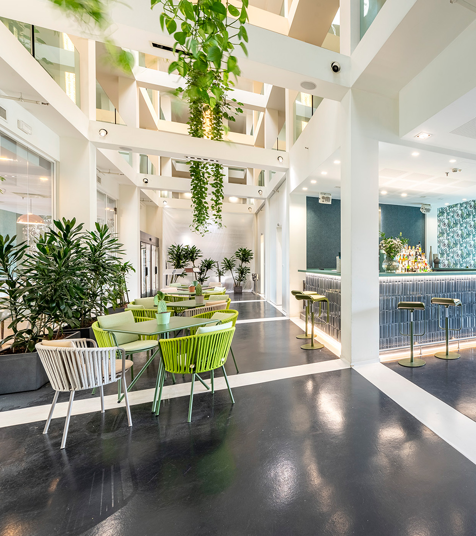 Spazio luminoso del bar con bancone moderno e tavoli circondati dal verde