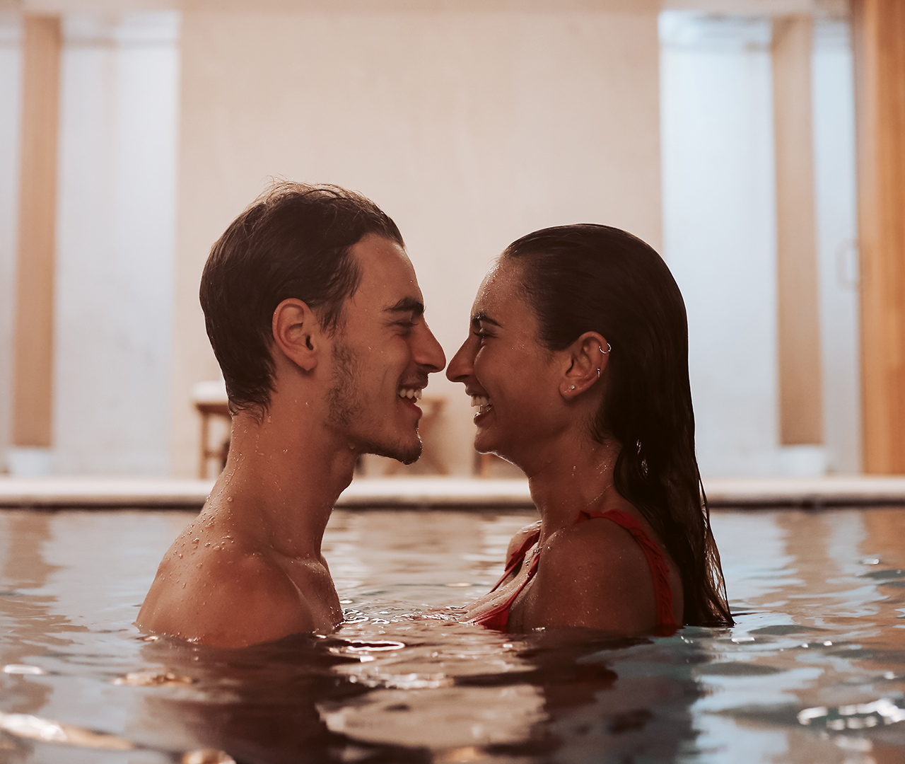 Coppia che sorride e si gode un momento romantico in piscina coperta