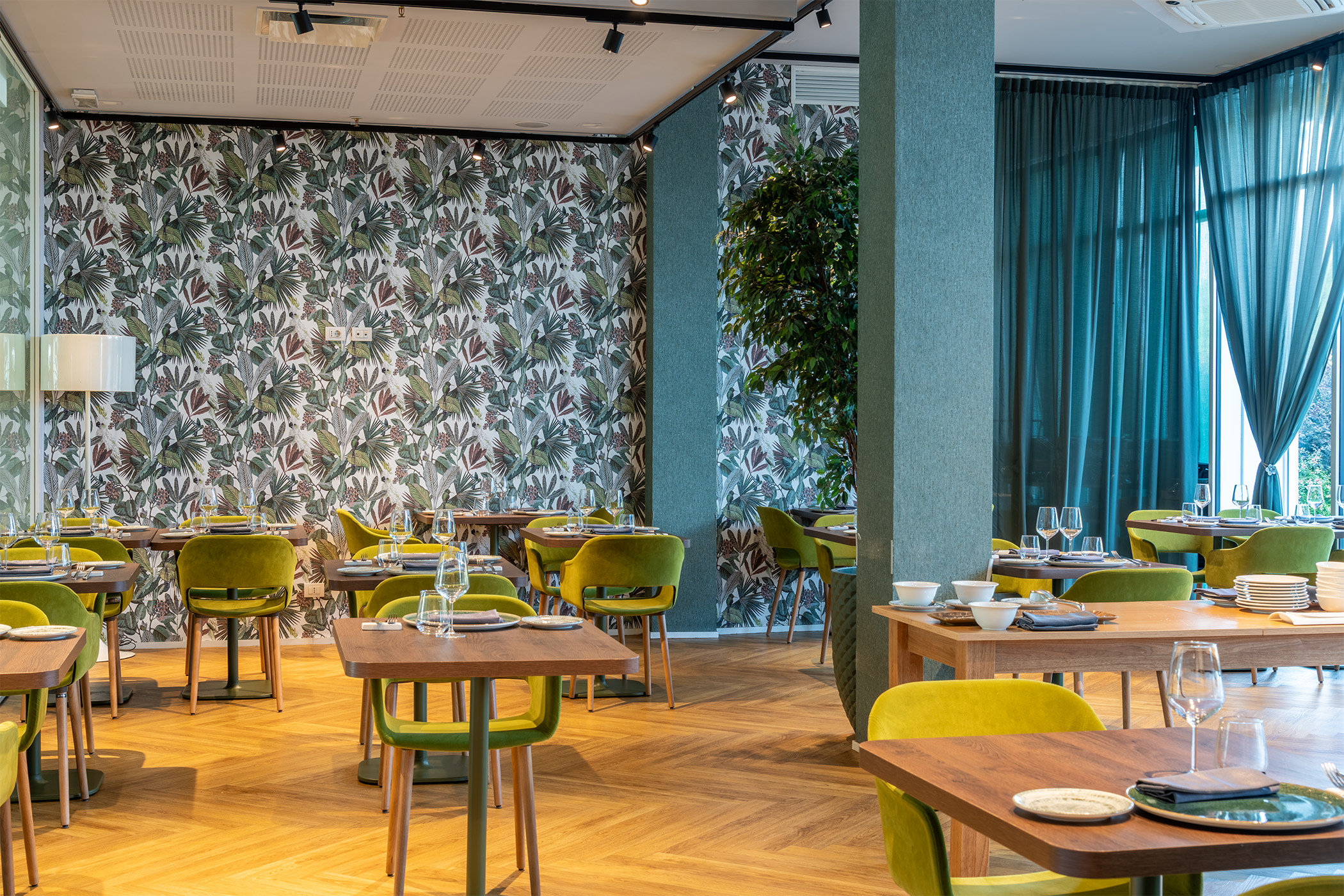 Sala interna del Bloom Restaurant & Lounge Bar al Moom Hotel, con tavoli apparecchiati, sedie di design e vista sul giardino