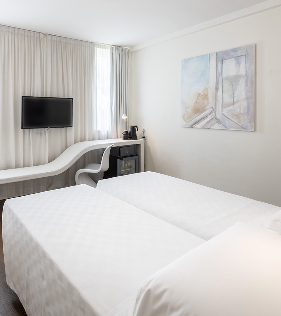 Camera Superior con letti singoli, panca bianca sotto la finestra con postazione scrivania integrata, TV a parete, minibar e ampie tende luminose